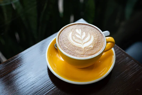 Sütlü sütlü sütlü sütlü sıcak kahve fincanı ahşap masanın üstünde. Kafedeki bir kafede kahvaltı olarak, iş konsepti sırasında, klasik tarzda.