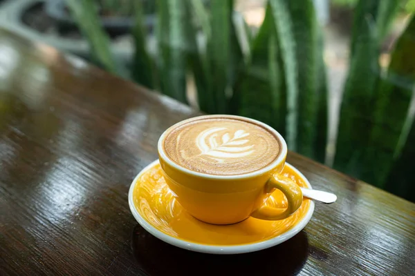 Sütlü sütlü sütlü sütlü sıcak kahve fincanı ahşap masanın üstünde. Kafedeki bir kafede kahvaltı olarak, iş konsepti sırasında, klasik tarzda.