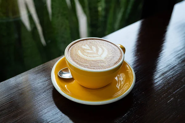 Sütlü sütlü sütlü sütlü sıcak kahve fincanı ahşap masanın üstünde. Kafedeki bir kafede kahvaltı olarak, iş konsepti sırasında, klasik tarzda.