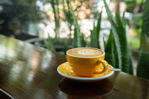 Sütlü sütlü sütlü sütlü sıcak kahve fincanı ahşap masanın üstünde. Kafedeki bir kafede kahvaltı olarak, iş konsepti sırasında, klasik tarzda.