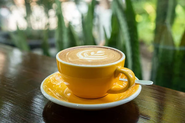 Sütlü sütlü sütlü sütlü sıcak kahve fincanı ahşap masanın üstünde. Kafedeki bir kafede kahvaltı olarak, iş konsepti sırasında, klasik tarzda.