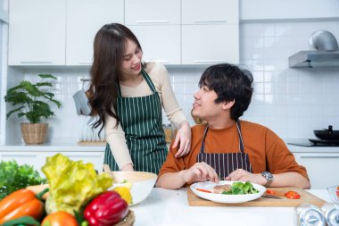 Mutlu Aile portresi, neşeli bir yemek hazırlayan neşeli bir Asyalı 'nın mutlu aile portresi. Mutfakta, et, ekmek ve sebzelerle yemek pişirmekten keyif alıyor.