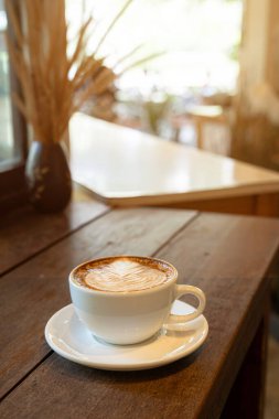 Sütlü sütlü sütlü sütlü sıcak kahve fincanı ahşap masanın üstünde. Kafedeki bir kafede kahvaltı olarak, iş konsepti sırasında, klasik tarzda.