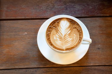 Sütlü sütlü sütlü sütlü sıcak kahve fincanı ahşap masanın üstünde. Kafedeki bir kafede kahvaltı olarak, iş konsepti sırasında, klasik tarzda.