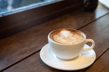 Sütlü sütlü sütlü sütlü sıcak kahve fincanı ahşap masanın üstünde. Kafedeki bir kafede kahvaltı olarak, iş konsepti sırasında, klasik tarzda.
