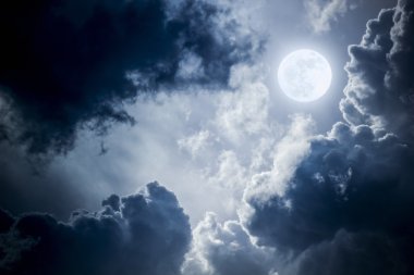 This dramatic photo illustration of a nighttime sky with brightly lit clouds and large, full, Blue Moon would make a great background for many uses.