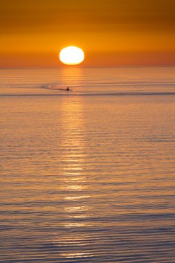 This fishing boat heads home from fishing in front of a beautiful sunset at Clearwater Beach, Florida in the Gulf of Mexico.
