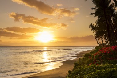 Beautiful, warm tropical sunset on the white sands of Kaanapali Beach in Maui, Hawaii. A fabulous destination for vacation and travel.
