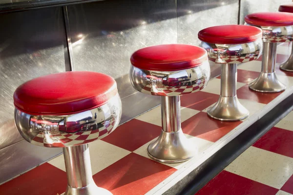 Warm morning sunlight highlights the simple but beautiful design of this classic diner counter with it's galvanized steel counter, bright chrome seats with red padding and bright red tiles. — Zdjęcie stockowe