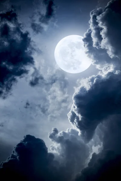 Esta dramática ilustración fotográfica de una escena nocturna con nubes brillantemente iluminadas y una Luna Azul grande y llena sería un gran fondo para muchos usos . Imagen de stock