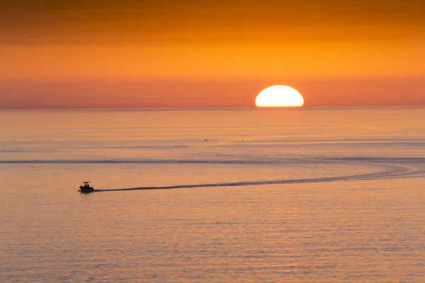 Este barco de pesca se dirige a casa de la pesca en frente de una hermosa puesta de sol en Clearwater Beach, Florida en el Golfo de México . Imagen de stock
