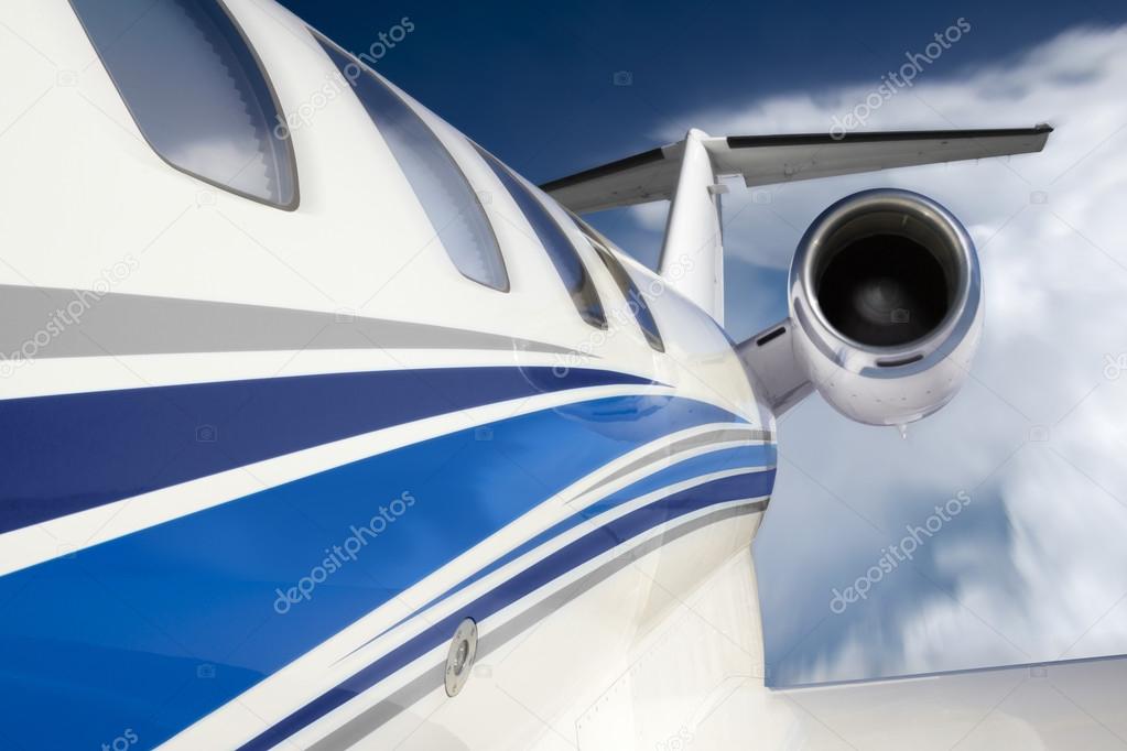 This photo illustration of a business jet is created from a unique in-flgiht perspective, from outside the aircraft, with slight motion blur, beautiful clouds and deep blue sky