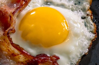 Kızarmış yumurta ve siyah tavada pastırma. Seçici odak.