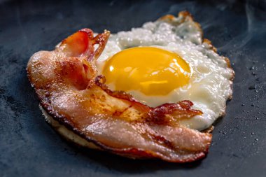 Kızarmış yumurta ve siyah tavada pastırma. Seçici odak.