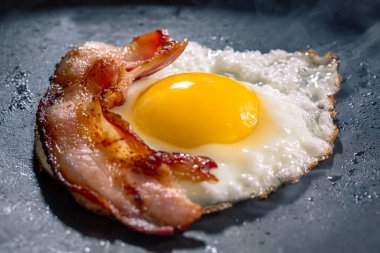 Kızarmış yumurta ve siyah tavada pastırma. Seçici odak.