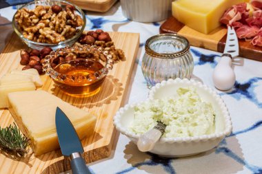 Different types of cheeses, wines, baguettes, fruits and snacks on the table for tasting and holiday scenery.