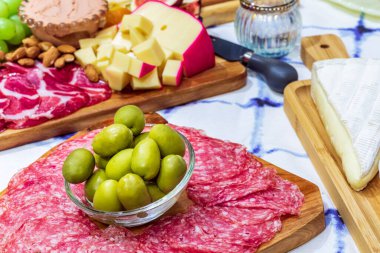 Different types of cheeses, wines, baguettes, fruits and snacks on the table for tasting and holiday scenery.