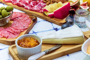 Different types of cheeses, wines, baguettes, fruits and snacks on the table for tasting and holiday scenery.