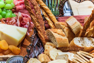 Different types of cheeses, wines, baguettes, fruits and snacks on the table for tasting and holiday scenery.