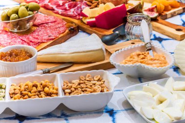 Different types of cheeses, wines, baguettes, fruits and snacks on the table for tasting and holiday scenery.
