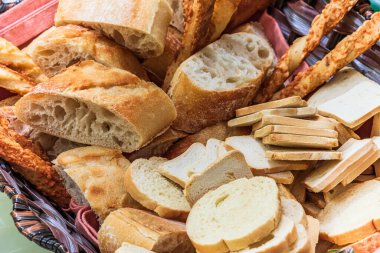 Basket of bread with different types of cheese on the table.
