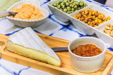 Brie cheese with apricot and snacks on the table for tasting and holiday scenery.