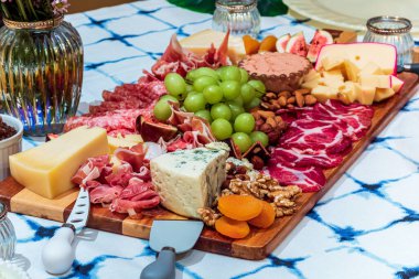 Different types of cheeses, wines, baguettes, fruits and snacks on the table for tasting and holiday scenery.