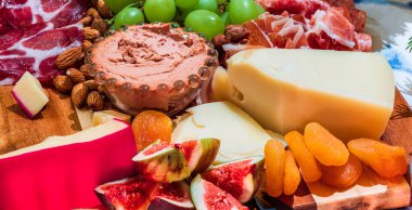 Different types of cheeses, wines, baguettes, fruits and snacks on the table for tasting and holiday scenery.