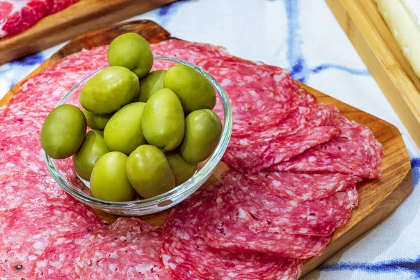 Different types of cheeses, wines, baguettes, fruits and snacks on the table for tasting and holiday scenery.