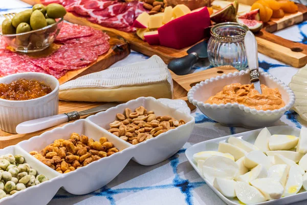 Different types of cheeses, wines, baguettes, fruits and snacks on the table for tasting and holiday scenery.