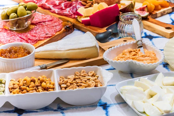 Different types of cheeses, wines, baguettes, fruits and snacks on the table for tasting and holiday scenery.