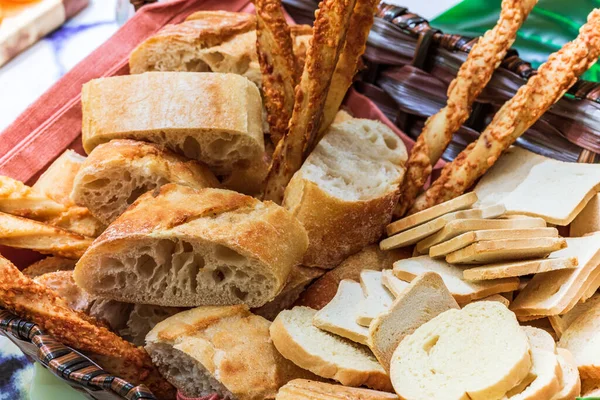 Basket of bread with different types of cheese on the table.