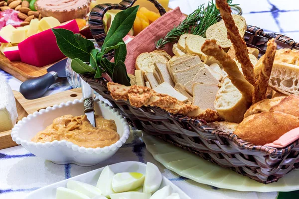 Different types of cheeses, wines, baguettes, fruits and snacks on the table for tasting and holiday scenery.