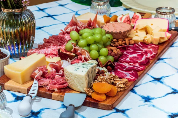 Different types of cheeses, wines, baguettes, fruits and snacks on the table for tasting and holiday scenery.