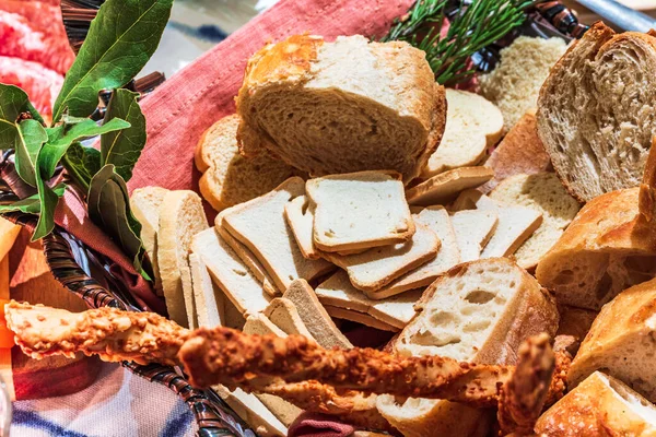 Different types of cheeses, wines, baguettes, fruits and snacks on the table for tasting and holiday scenery.