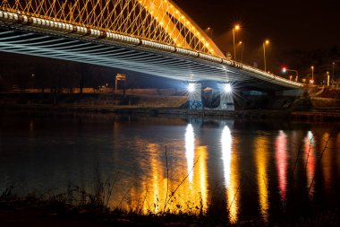 Nehrin üzerinde ışıkları olan modern bir köprü. Güzel şehir mimarisi. Çelik yapı.