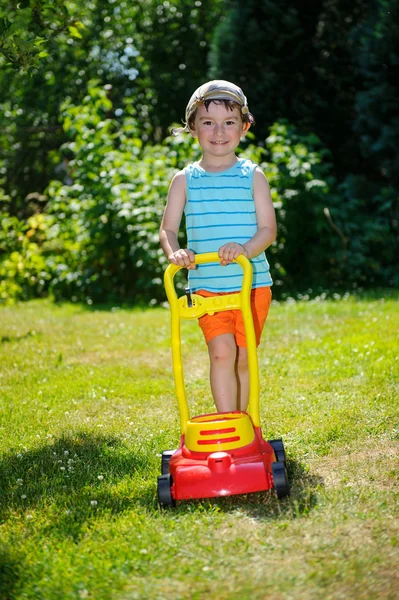 Happy small boy help with gardening with his lawn mower — Stock Photo, Image