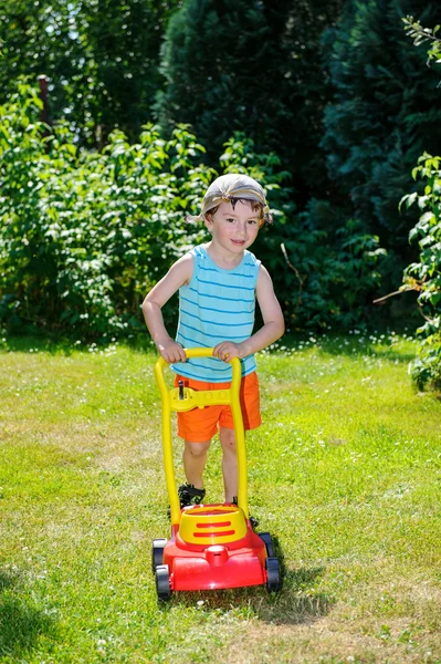 Happy small boy help with gardening with his lawn mower — Stock Photo, Image