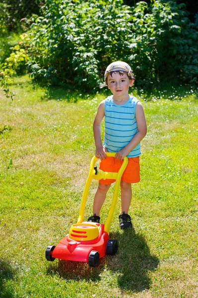 Happy small boy help with gardening with his lawn mower — Stock Photo, Image