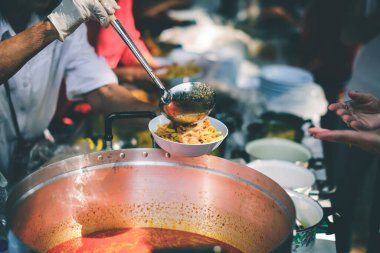 Yoksullarla paylaşmak için yiyecekleri kepçeleyen gönüllüler: Dilencilere bedava yemek kavramı