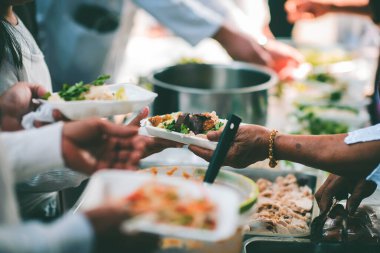 Yoksullarla paylaşmak için yiyecekleri kepçeleyen gönüllüler: Dilencilere bedava yemek kavramı