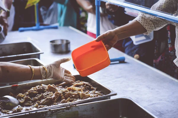 Volunteers scooping the food to share with the needy : concept of free food to beggars