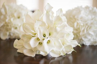 Parlak ahşap yüzeyde üç beyaz zambak buketi