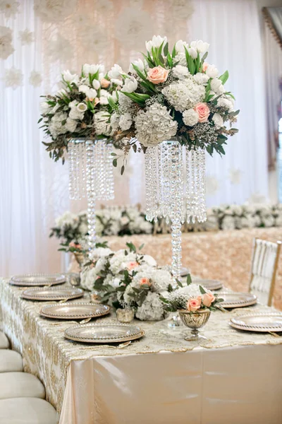 Tall wedding reception centerpieces with crystals and hydrangeas and white and pink flowers on gold table setting