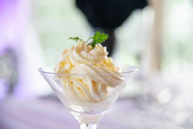 Şık yemek masasında çırpılmış tereyağı ve fesleğenle dolu martini bardağı.