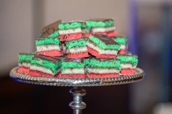 Delicious Italian Rainbow cookies stacked on silver cookie tray at dessert bar