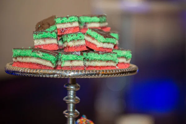 Delicious Italian Rainbow cookies stacked on silver cookie tray at dessert bar