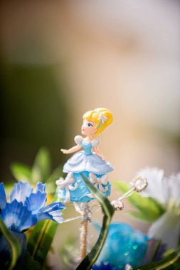 Mavi çiçeklerle çevrili mavi ve beyaz elbiseler giyen sarı Külkedisi pasta üstlüğü