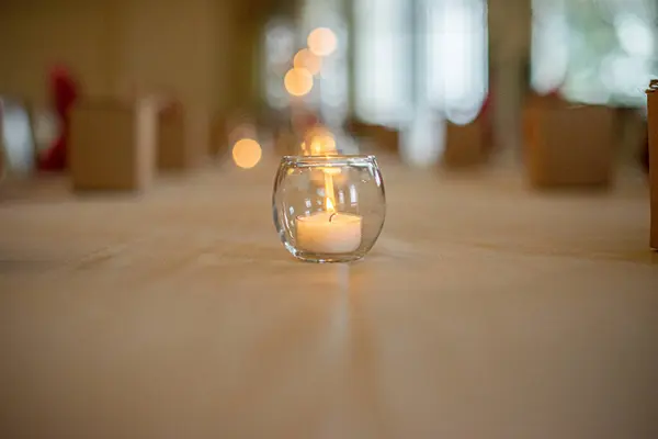 Round glass candle holder with lit candle on luxury dinner table setting