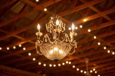 Bir ahırın ahşap kiriş tavanından sarkan Viktorya dönemi şansölyesi